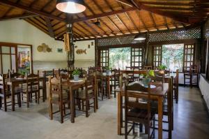 a restaurant with wooden tables and chairs in a room at Pousada Villa Cumuru in Cumuruxatiba