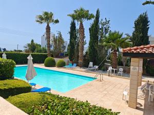 a swimming pool in a resort with palm trees at Sunset Green 03 in Paphos
