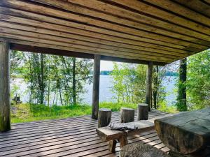 a wooden deck with a table and benches on a lake at Saimaa Lakeside Sauna Cabin in Taipalsaari