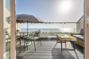 a balcony with a table and chairs and an umbrella at Sunset Townhouse – Pwllheli in Pwllheli