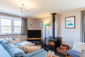 un soggiorno con un divano blu e una TV di Ivy Cottage - Little Haven a Little Haven