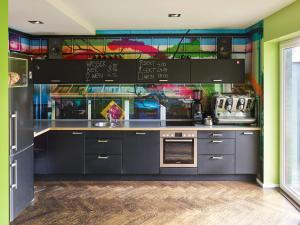 a kitchen with grey cabinets and a colorful wall at Das kleine Schwarze - Bed & Breakfast in Hamburg