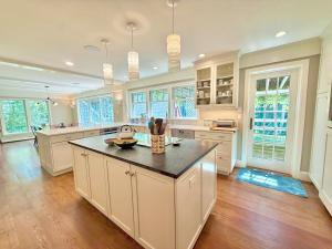 a large kitchen with white cabinets and a black counter top at Beautiful House in the Woods, Huge Yard, Hot Tub in Great Barrington