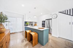 a kitchen with white walls and a blue island with stools at Riverbreeze - Close to Hastings 3 bed AC Pool in Noosa Heads