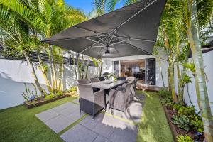 a patio with a table and chairs and an umbrella at Riverbreeze - Close to Hastings 3 bed AC Pool in Noosa Heads