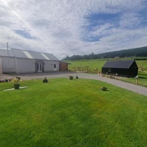 a large green yard with a building and a grass field at Pleasant Point Holiday Cottages in Glenurguhart
