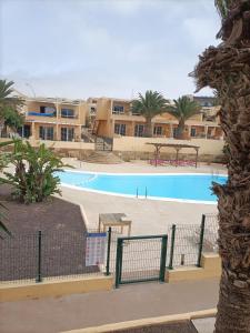 a swimming pool in a resort with palm trees and buildings at Casa Serena in Costa Calma