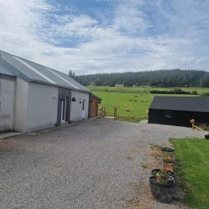 a barn with a gravel driveway next to a field at Pleasant Point Holiday Cottages in Glenurguhart