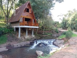 a log cabin with a creek in front of it at Pousada do Aconchego in São Salvador