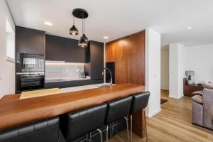 a kitchen with a bar with black leather chairs at Praia Mar Apartamento T2 in Esposende