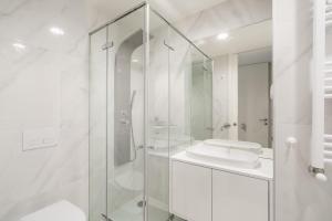 a white bathroom with a shower and a sink at Praia Mar Apartamento T2 in Esposende +13 photos