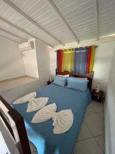 a bedroom with a blue bed with towels on it at Pousada é in Cumuruxatiba