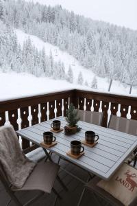 a table on a balcony with snow covered trees at Le Cocon Pyrénéen - Ski aux pieds & Parking Privé in Les Angles