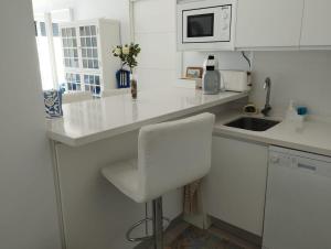 a white kitchen with a white chair and a sink at Sueños del Mediterraneo Estudio in Melicena