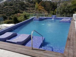 a swimming pool with two cushions and a wooden deck at Sueños del Mediterraneo Estudio in Melicena