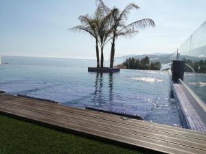 a swimming pool with a palm tree next to the ocean at Sueños del Mediterraneo Estudio in Melicena