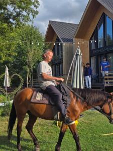 a man riding a horse in front of a house at 4 Chalet near Borjomi in Borjomi +33 photos