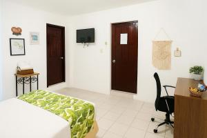 a bedroom with a bed and a desk and a tv at Costa Verde Hostal in Manta