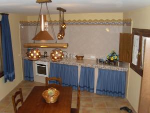 cocina con cortinas azules, mesa y encimera en Casa Rural Del Antiguo Hojalatero, en Ibdes