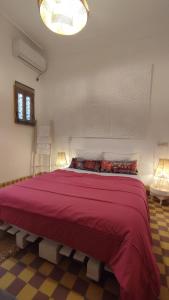 Maison en exclusivité 2 chambre Place Jemma El Fna في مراكش: غرفة نوم بسرير احمر كبير مع مصباحين