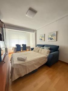 ブルゴスにあるGlorieta del Peregrino en Burgosのベッドと青いソファのある寝室