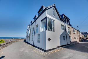 una casa bianca con una finestra sulla spiaggia di Coot's Nest Seahouses a Seahouses