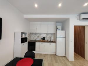 eine Küche mit einem weißen Kühlschrank und einem roten Tisch in der Unterkunft Benicarló Vacation Apartment in Benicarló + 13 Fotos