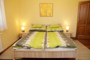 a bed with green sheets and pillows in a bedroom at Boróka Vendégház in Szentes