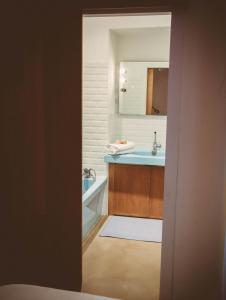 een badkamer met een wastafel, een bad en een spiegel bij La terrasse de la comédie in Montpellier