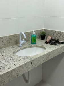 a bathroom counter with a sink and a bottle of soap at Casa para 5 pessoas - Perto de Tudo in Montes Claros