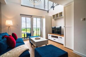a living room with a blue couch and a tv at Morze Apartamentów Apartament West Łeba A19 in Łeba
