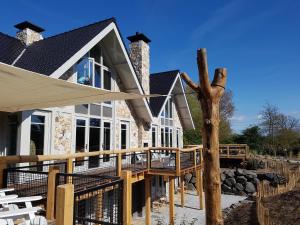 a house with a wooden deck and a tree at Holiday Home with bubble bath in Noordwijk in Noordwijk +34 photos