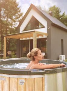 a woman in a hot tub in front of a house at Osada pod Gwiazdami & SPA - FAMILY ogrodzony dom, prywatne JACUZZI, kominek, grill, ognisko, Kajaki, Plaża, Jeziora in Łasko