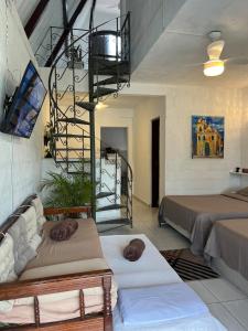 a room with two beds and a spiral staircase at Casa estilo chale dúplex com 3 quartos, churrasqueira, balanço, chuveirão e a uma quadra da praia in Mangaratiba