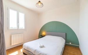 a bedroom with a large white bed with an arch at TiArMor Saint-Brieuc Ville in Saint-Brieuc