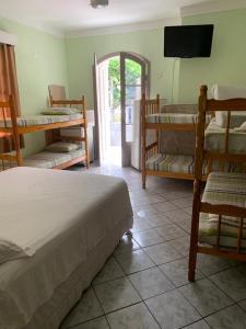 a bedroom with bunk beds and a flat screen tv at Pousada Ohana Guarujá in Guarujá