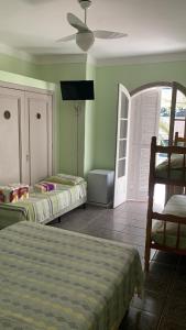 a bedroom with two beds and a ceiling fan at Pousada Ohana Guarujá in Guarujá