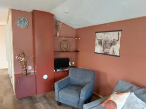 salon z krzesłem i zegarem na ścianie w obiekcie Nette, ruime chalet op christelijke familiecamping w mieście Rheeze