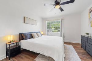 a white bedroom with a bed and a ceiling fan at 20 Minute Walk to Tiger Stadium / King Bed in Beaulieu
