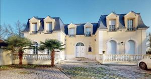 a large white house with a palm tree in front of it at Luxury trip to Alice's Country in Quincy-sous-Sénart