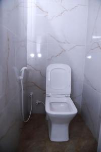 a white bathroom with a toilet and a phone at Stellar Bunks in Peradeniya