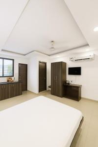 インドールにあるHomezype Homes Luxury Stayの大きなベッドとテレビのある白い寝室