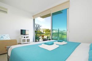 Un dormitorio con una cama azul con una ventana grande. en Too Coool Studio Apartment Coralli Resort, en Protaras