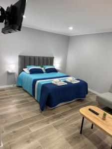 a bedroom with a bed with blue sheets and a television at Casa Camacho - Santa Cruz in Santa Cruz