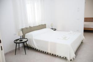 a white bed in a white room with a window at Dimora del Centro in Marsala
