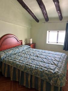 una camera da letto con un letto con un piumone blu e una finestra di Casa Rural Villa María a Liétor
