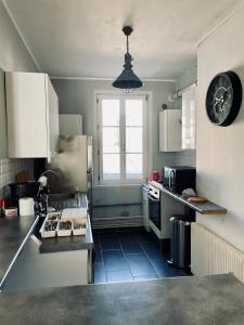 a kitchen with a refrigerator and a clock on the wall at Appartement 80m2 à deux pas du beffroi in Arras