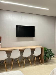 a conference room with a table and four white chairs at Flat aconchegante - Perto de Tudo - Vista Livre - Estacionamento privativo e Portaria 24h - Wi-Fi 600mbps in Brasilia