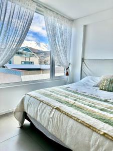 a bedroom with a bed and a large window at Austral Apartamentos in Ushuaia