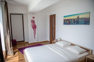a bedroom with a white bed and a painting on the wall at Sea Gem Mamaia - 200m to Beach, XL Terrace, and Beautiful Views in Mamaia